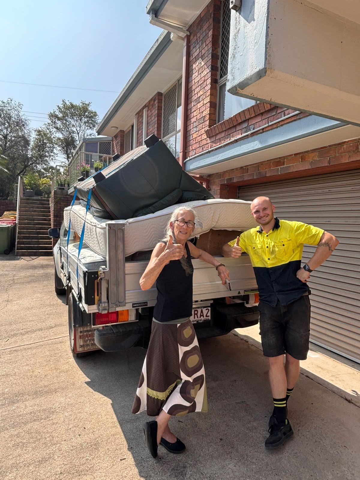 Pickup Pals removalist and a happy customer beside a ute loaded with a couch and mattresses for the tip